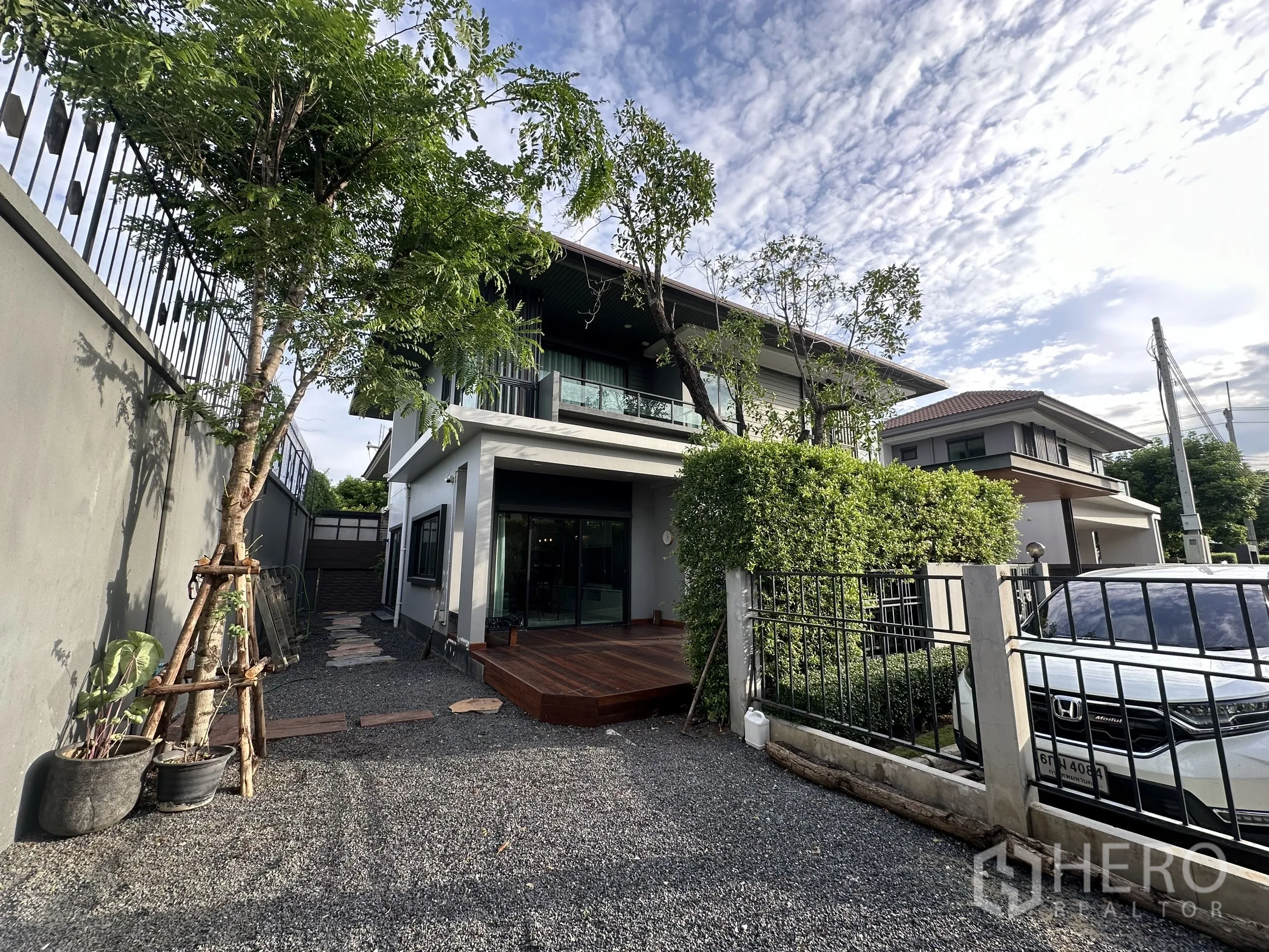 บ้าน ให้เช่าหรือขายในLam Luk Ka, Pathum Thani - ลานหน้าบ้านและทางรถเข้า มีต้นไม้ รั้วเหล็ก และพื้นกรวด มองเห็นตัวบ้าน