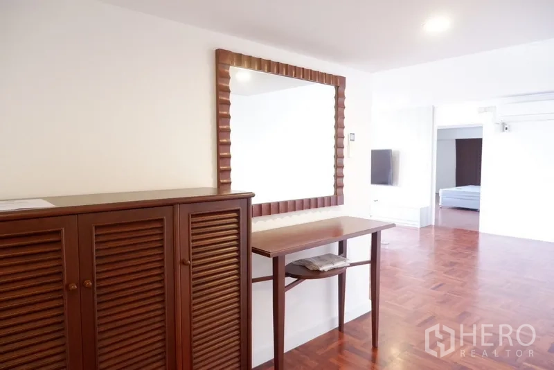 公寓 出租在Khlong Toei, Bangkok - 近景展示木百叶柜与镜面梳妆台，旁接卧室