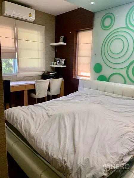 独立式住宅 出租在Prawet, Bangkok - 温馨卧室，白色床、书桌与绿色圆形装饰墙。