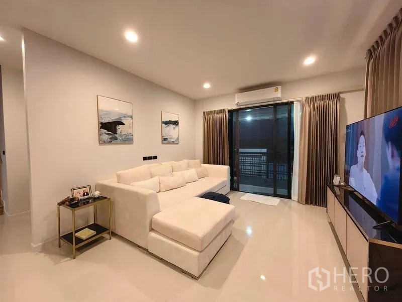 独立式住宅 出租在Bang Kapi, Bangkok - 温馨客厅，白色L形沙发、推拉落地门与电视柜