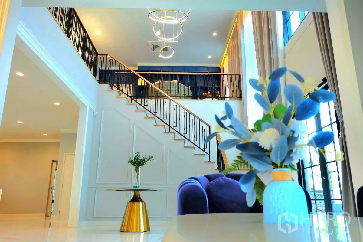 独立式住宅 出租在Bang Phli, Samut Prakan - 挑高客厅，铁艺楼梯与设计感吊灯相映成趣。