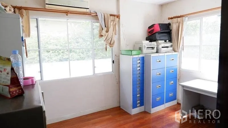 Detached House for rent in Prawet, Bangkok - Light-filled study room with filing cabinets, desk and wood flooring.