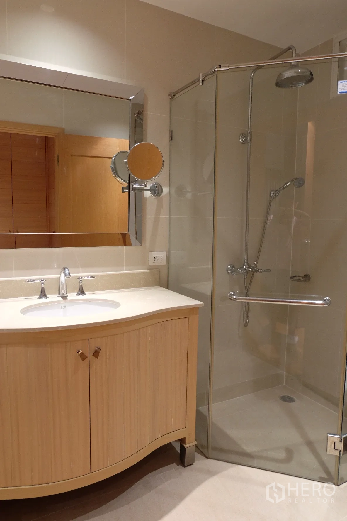 Condominium for rent in Sathon, Bangkok - Bathroom with large mirror, light-wood vanity and a glass-enclosed walk-in shower.