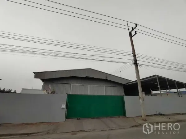 货栈 出售在Lam Luk Ka, Pathum Thani - 仓库正门街景，金属围墙与绿色大门