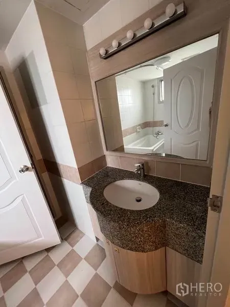 公寓 出租在Watthana, Bangkok - 花岗岩台面洗手台，大镜与灯具，可见带浴缸的浴室。