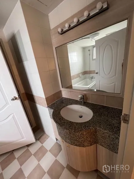 公寓 出租在Watthana, Bangkok - 花岗岩台面洗手台，大镜与灯具，可见带浴缸的浴室。