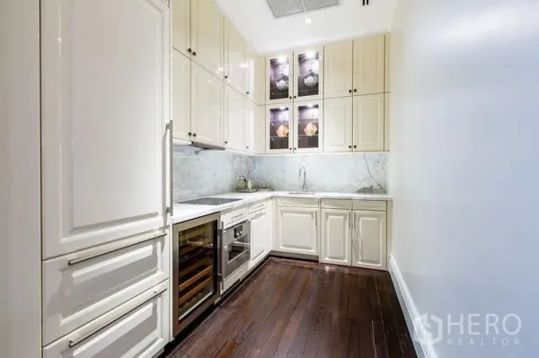 Condominium for sale in Pathum Wan, Bangkok - Enclosed gourmet kitchen with cream cabinetry, marble backsplash, built-in oven and wine fridge.