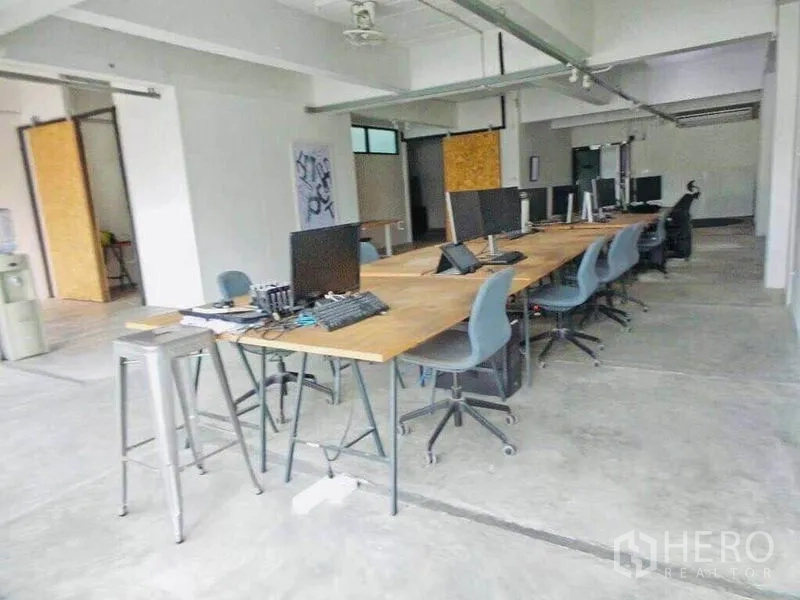 带办公室的家 出租或出售在Din Daeng, Bangkok - 长条共享工位，木质桌面，办公椅与外露天花。