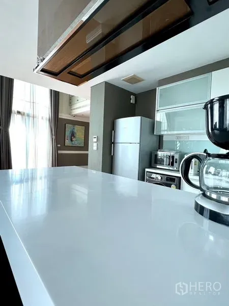 คอนโด ให้เช่าในKhlong Toei, Bangkok - เคาน์เตอร์ท็อปสีขาวแบบบาร์ในครัวสว่างพร้อมเครื่องชงกาแฟและผ้าม่านสูง