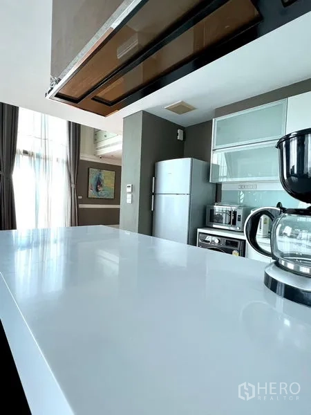 คอนโด ให้เช่าในKhlong Toei, Bangkok - เคาน์เตอร์ท็อปสีขาวแบบบาร์ในครัวสว่างพร้อมเครื่องชงกาแฟและผ้าม่านสูง