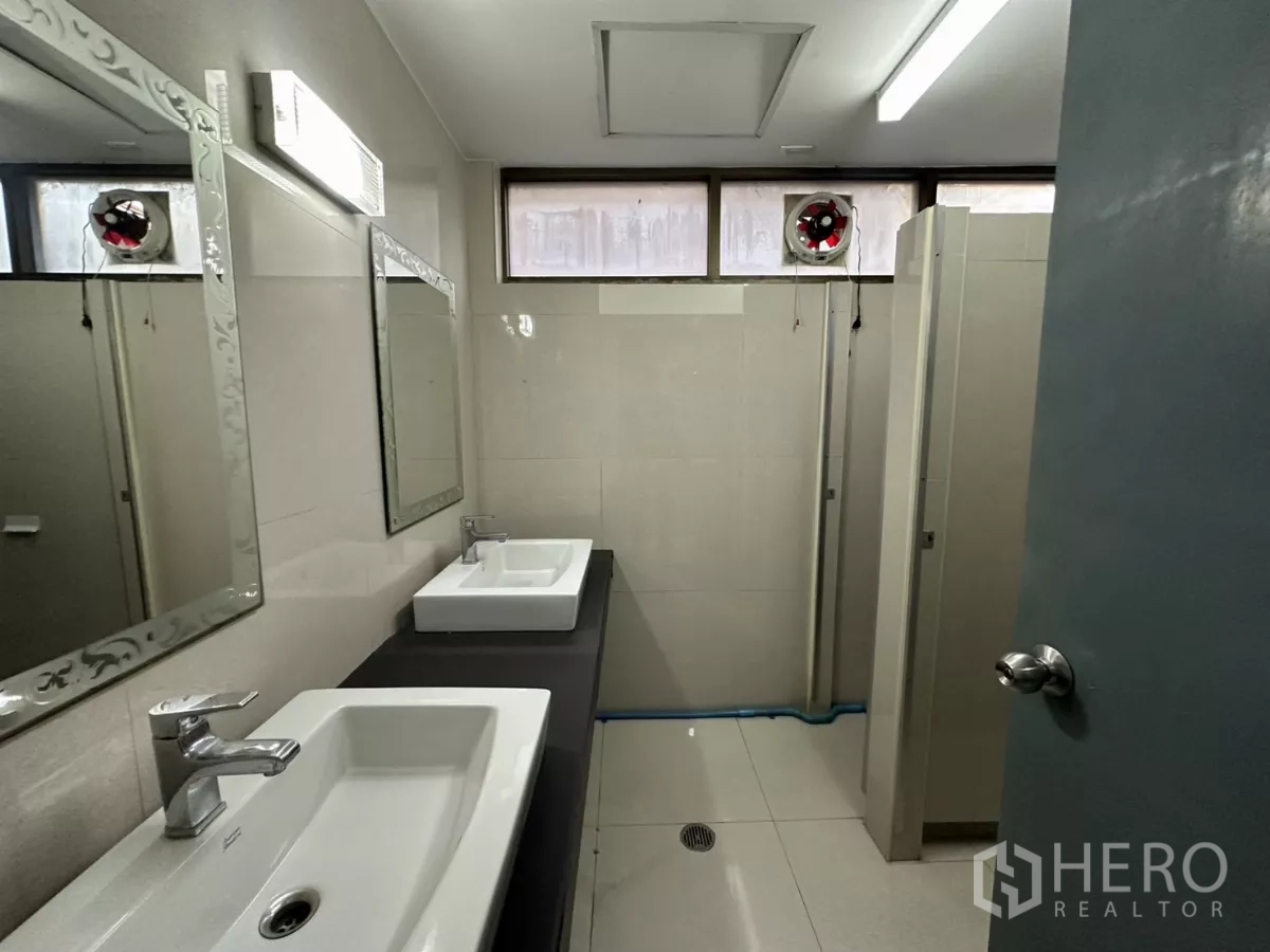 办公空间 出租 - 整洁卫生间，洗手台、镜子与隔间门。