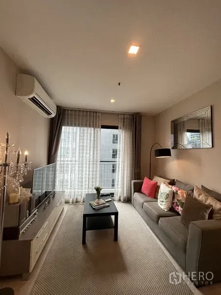 คอนโด ให้เช่าหรือขายในKhlong Toei, Bangkok - ห้องนั่งเล่นสว่างด้วยหน้าต่างเต็มบาน โซฟาสีเทา ทีวี และผ้าม่านโปร่ง