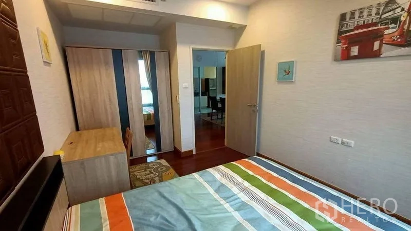 คอนโด ขาย - ห้องนอนพร้อมตู้เสื้อผ้า โต๊ะ และมุมมองไปทางโถงและห้องนั่งเล่น