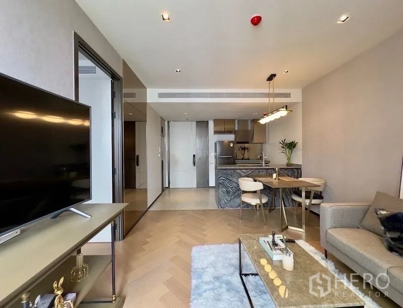 公寓 for rent or sale in Watthana, Bangkok - 客厅设电视柜与地毯，可见厨房和用餐吧台。