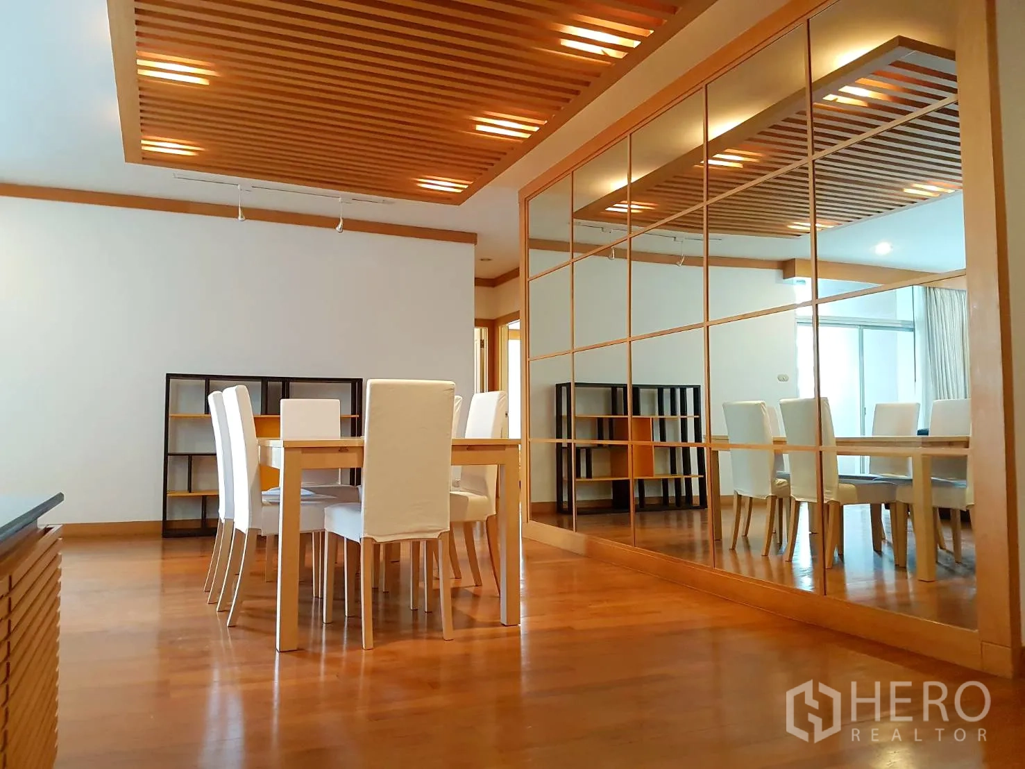 Condominium for rent in Pathum Wan, Bangkok - Bright dining area with wooden slat ceiling, mirror feature wall and hardwood floors in a Bangkok condo.