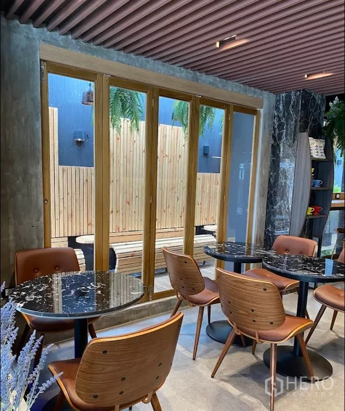 พื้นที่ขายปลีก ให้เช่าในKhlong Toei, Bangkok - โซนนั่งทานในร่มพร้อมโต๊ะหินอ่อนกลม เก้าอี้หนัง และประตูกระจกเต็มสูง