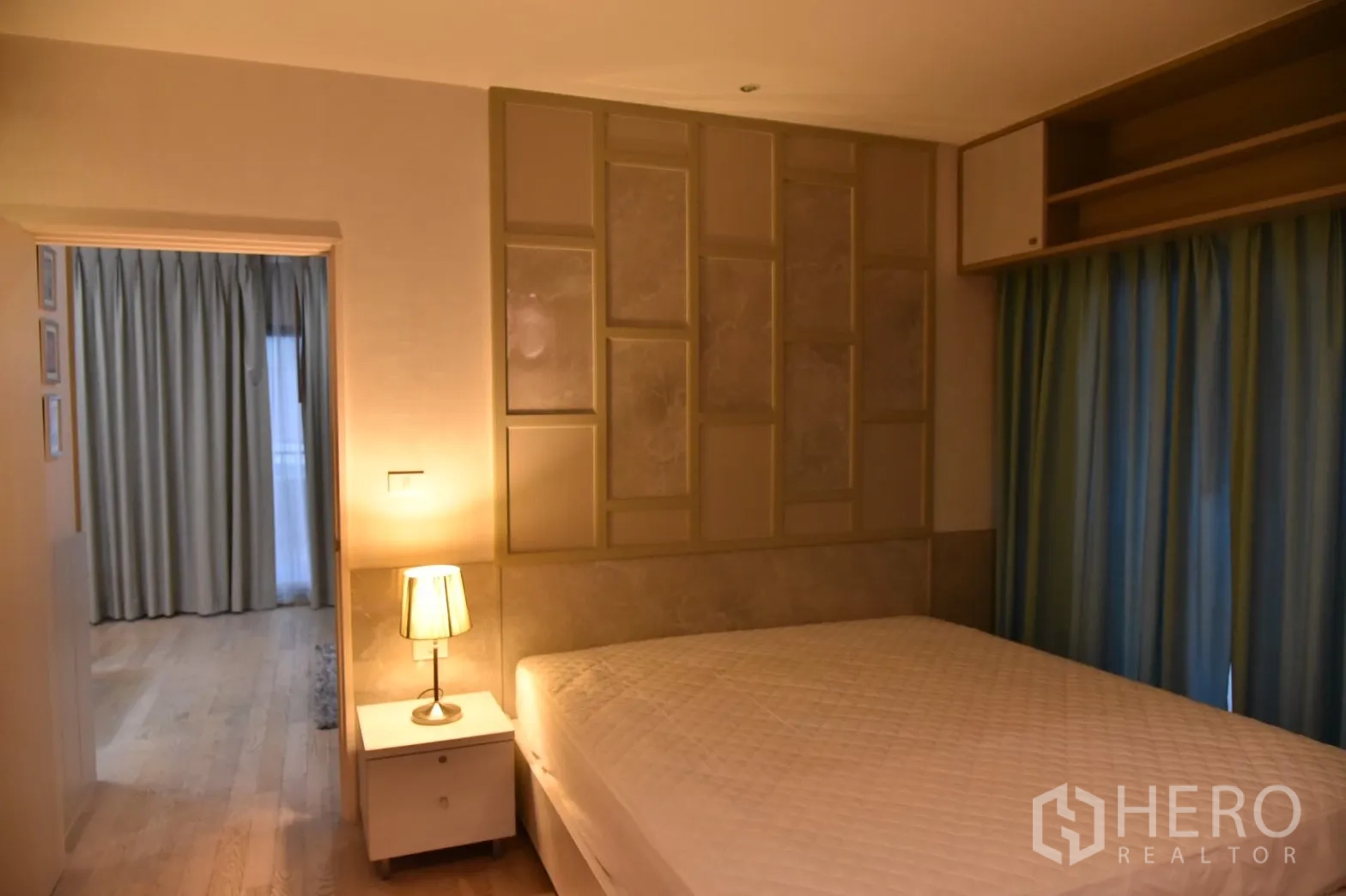 Condominium for rent or sale in Khlong Toei, Bangkok - Warm bedroom with king-size bed, bedside lamp and decorative panel headboard.
