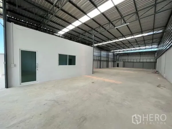 Warehouse for rent in Krathum Baen, Samut Sakhon - Spacious warehouse interior with high steel roof, skylight panels, smooth concrete floor and a built‑in office room.