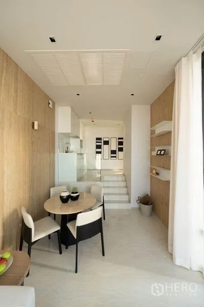 公寓 出租在Bang Rak, Bangkok - 圆桌餐区临窗，通往紧凑厨房与台阶过道。