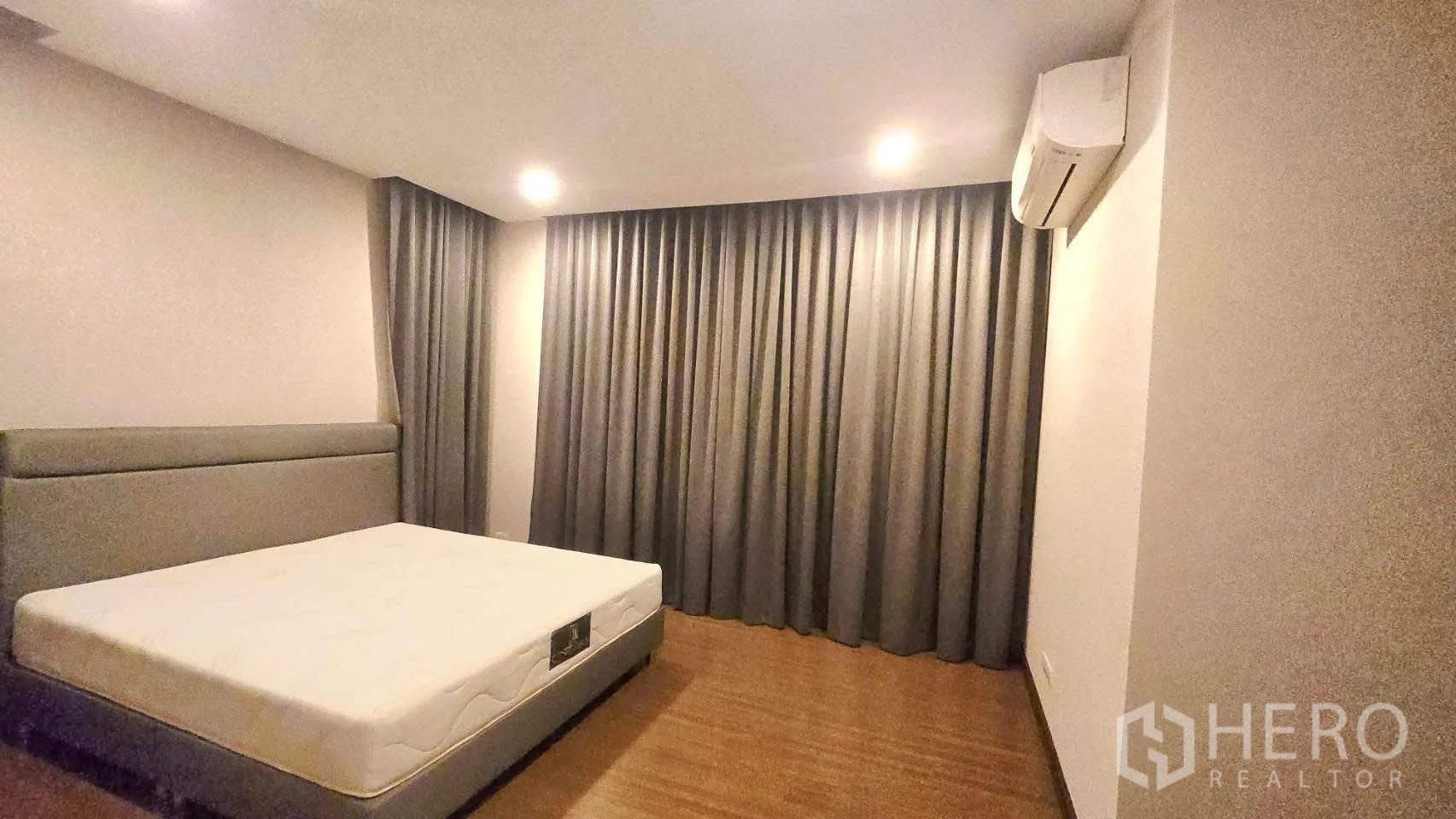 Detached House for rent in Prawet, Bangkok - Bedroom with upholstered bed, air conditioner, wood floor and blackout curtains.