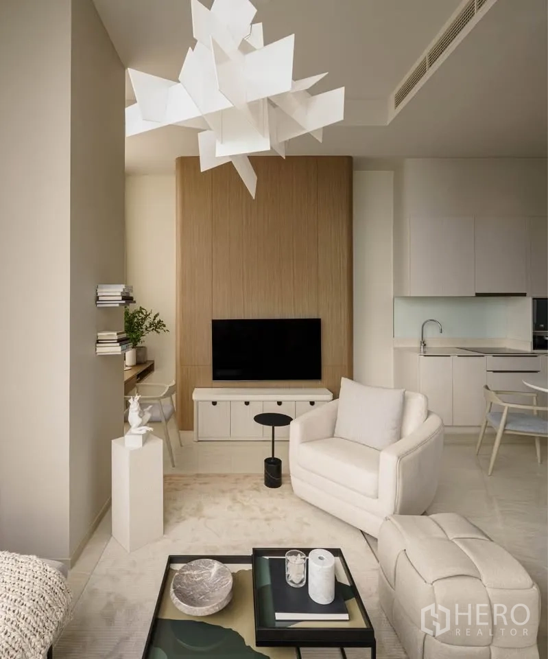 Condominium for rent in Bang Rak, Bangkok - Living room with modern chandelier, TV wall, and neutral-toned seating.