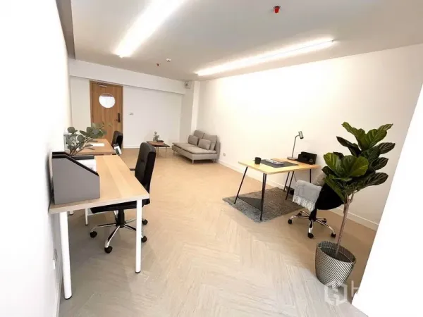 Office Space for rent in Khlong Toei, Bangkok - Minimalist private office with desks, ergonomic chairs, sofa seating and a tall plant under linear lights.