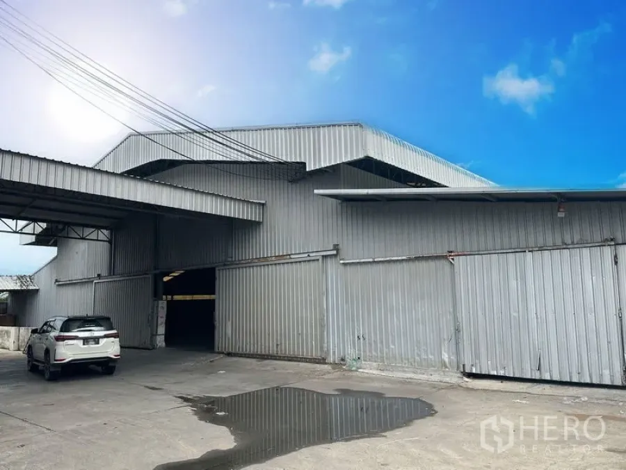 工厂 出租在Lat Lum Kaeo, Pathum Thani - 工业建筑正面，大型金属推拉门、带顶装卸雨棚与停车区。