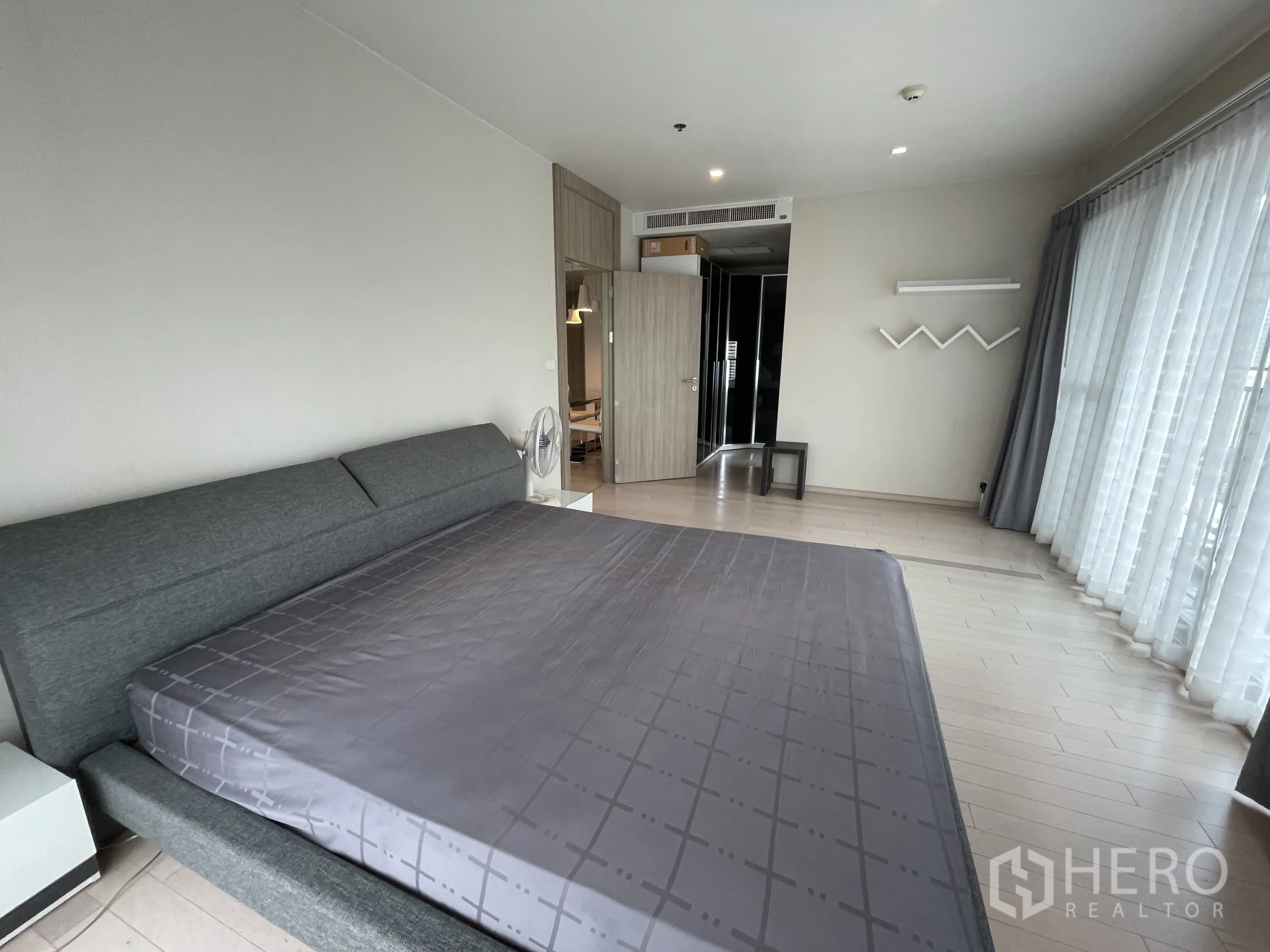 公寓 出租在Watthana, Bangkok - 宽敞卧室，双人床、浅色木地板与环绕落地窗及纱帘。