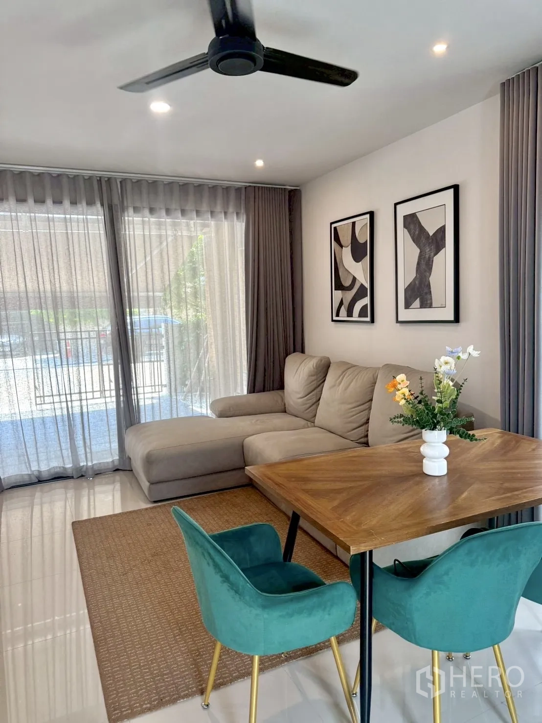 联排别墅 for rent in Prawet, Bangkok - 客厅设转角沙发、餐桌、吊扇与落地窗帘。