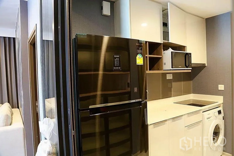 คอนโด ให้เช่าในHuai Khwang, Bangkok - ครัวบิลท์อินของคอนโดกรุงเทพฯ ตู้เย็นสีดำ ไมโครเวฟ เตาไฟฟ้า และเครื่องซักผ้า