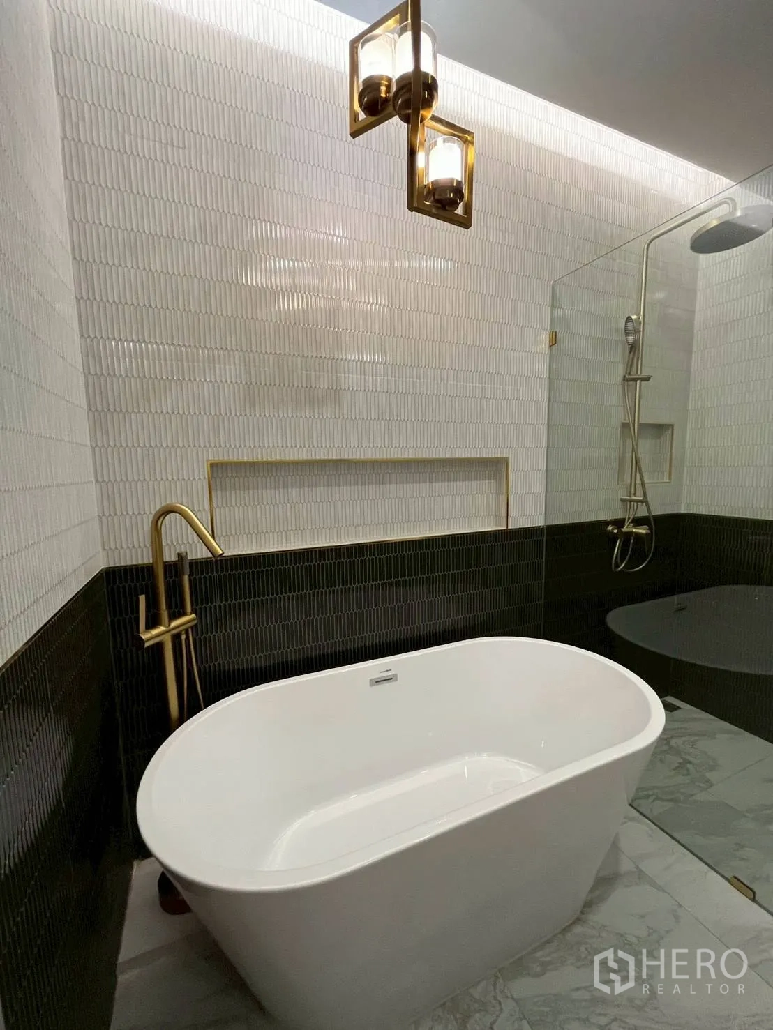 ทาวน์เฮาส์ for rent in Khlong Toei, Bangkok - ห้องน้ำโมเดิร์นมีอ่างอาบน้ำแบบลอยตัว ชุดก๊อกสีทอง ฝักบัวกระจก และผนังไทล์ลาย.