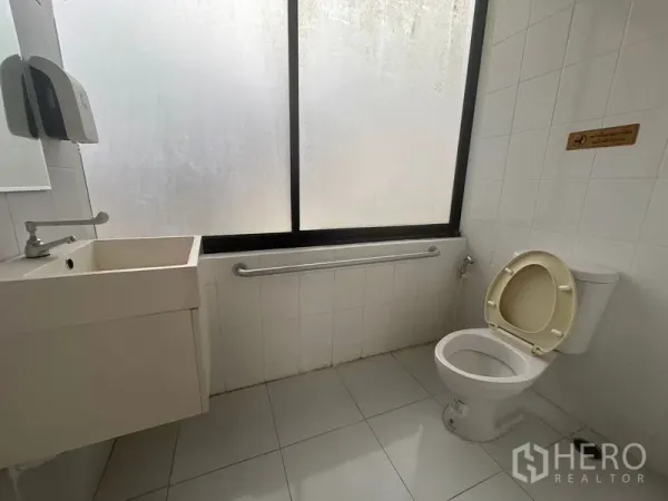 办公空间 出租在Bang Rak, Bangkok - 第二间卫生间，磨砂窗、壁挂洗手盆、坐便器与安全扶手。