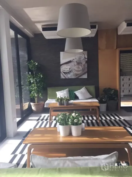 ทาวน์เฮาส์ ให้เช่าหรือขายในLat Phrao, Bangkok - ห้องนั่งเล่นสว่าง กระจกบานใหญ่ โคมแขวน โซฟาสีเขียว และโต๊ะไม้พร้อมกระถางต้นไม้