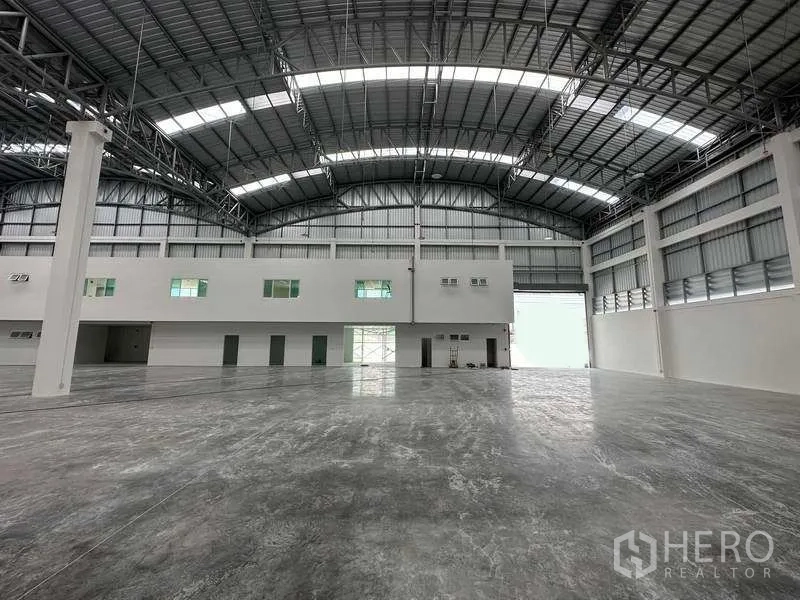 Factory for rent in Khlong Luang, Pathum Thani - Vast internal space looking toward roller shutter entry and white office core.