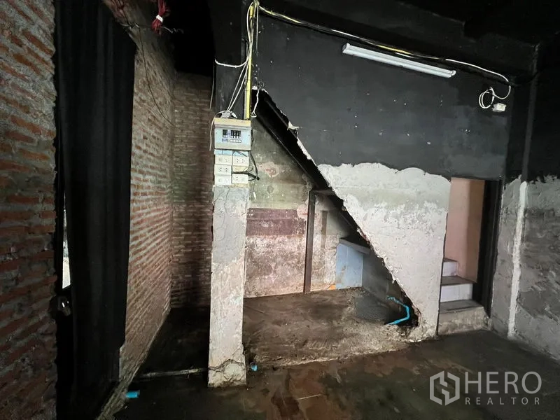 店屋 出租在Phaya Thai, Bangkok - 楼梯下角落，外露红砖、配电箱与水泥表面