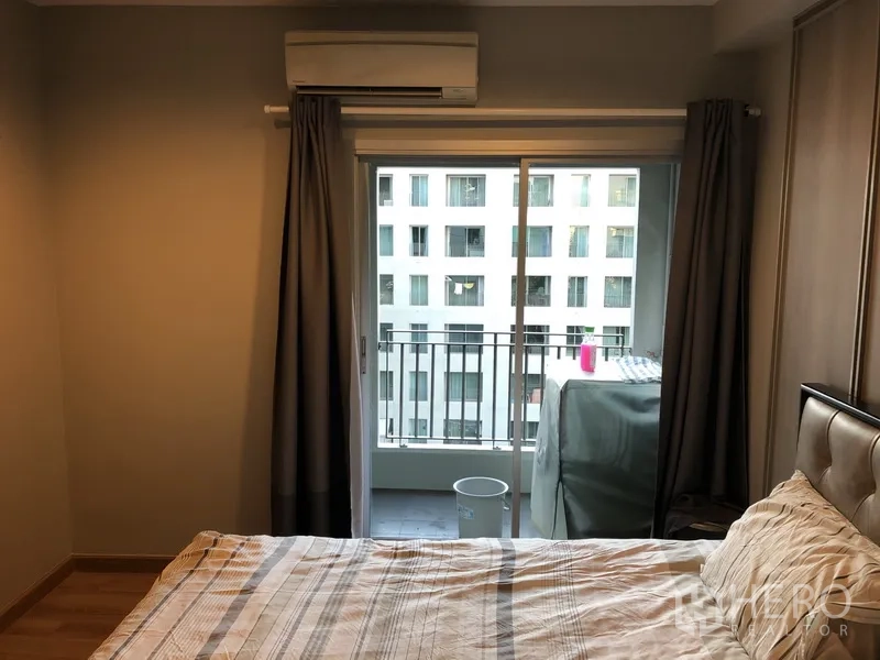 คอนโด ให้เช่าในPathum Wan, Bangkok - ห้องนอนมีประตูบานเลื่อนไปยังระเบียงและเครื่องปรับอากาศ มองเห็นอาคารใกล้เคียง