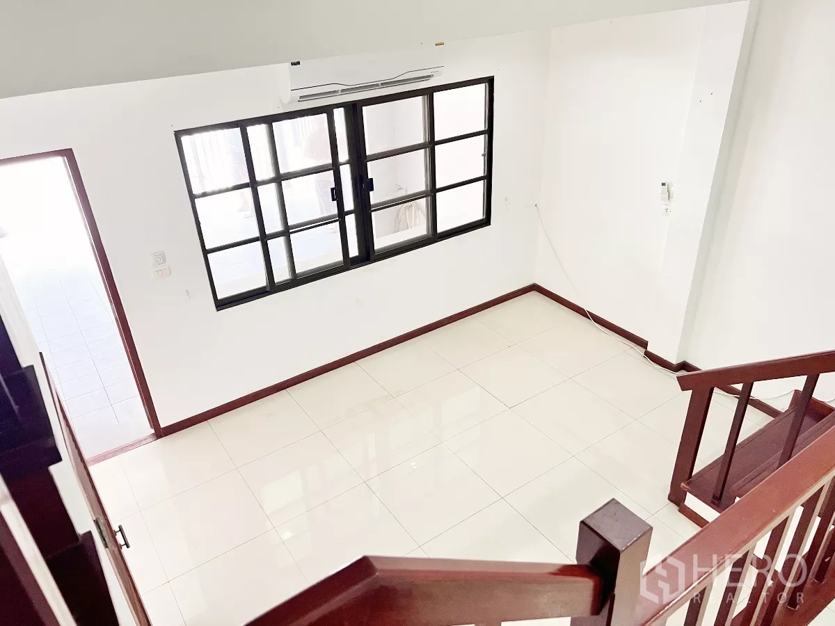 ทาวน์เฮาส์ ให้เช่าหรือขายในPhra Khanong, Bangkok - มุมมองจากบันไดลงสู่โถงสว่าง พื้นกระเบื้องและหน้าต่างบานเลื่อน