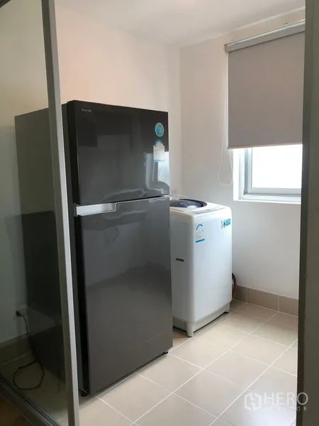 Condominium for rent in Huai Khwang, Bangkok - Utility area with large refrigerator and top-load washing machine beside a window.