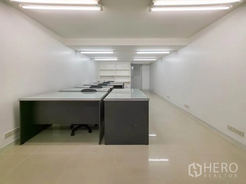 สำนักงาน ให้เช่าในKhlong Toei, Bangkok - ห้องทำงานลึกยาว จัดวางโต๊ะทำงานหลายตัวใต้ไฟนีออน.