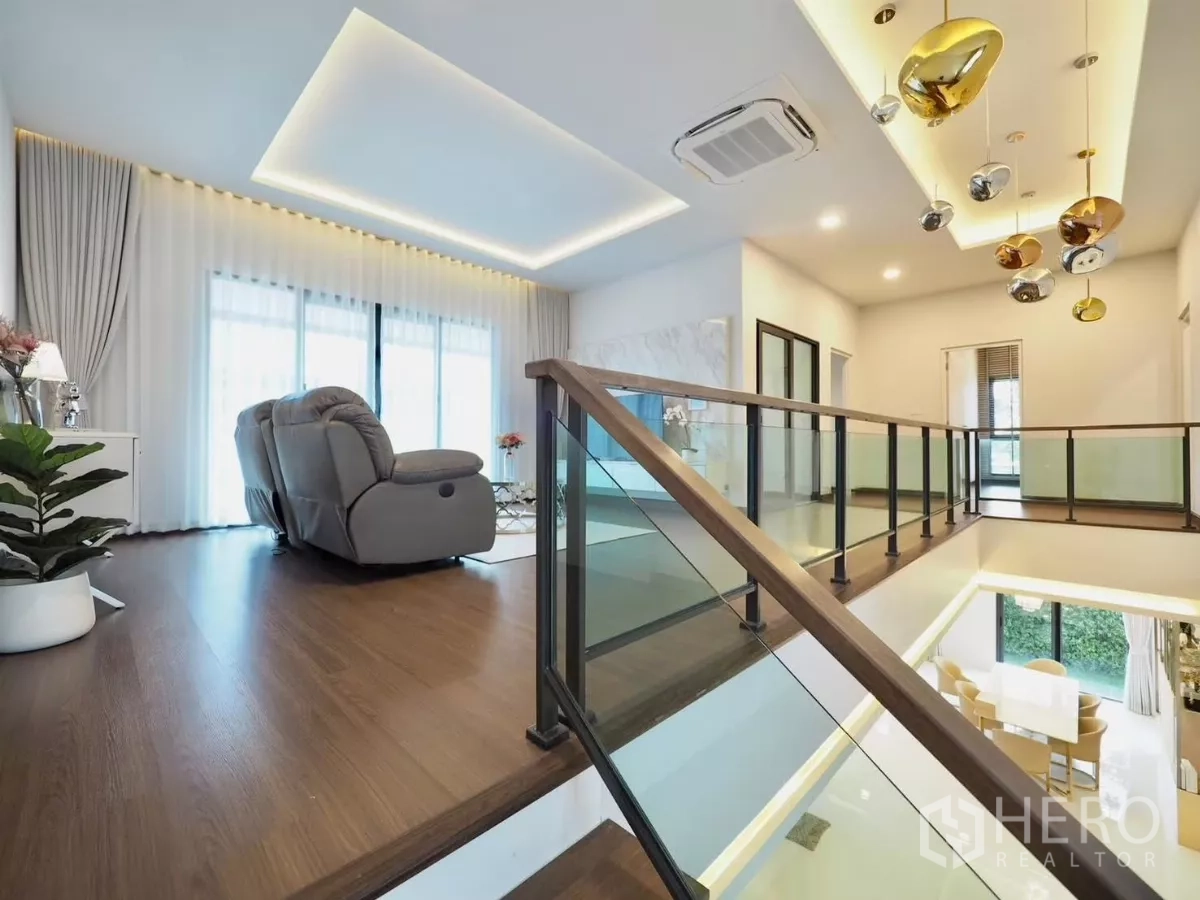 Detached House for rent in Bang Phli, Samut Prakan - Upstairs family lounge by the staircase with glass railing and wood floors.