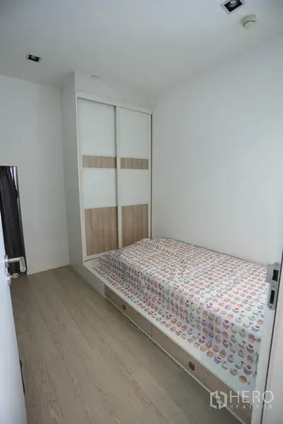 Condominium for rent or sale in Watthana, Bangkok - Compact second bedroom with single bed, light wood flooring, and built-in sliding wardrobe.