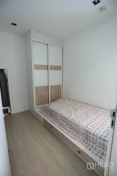 Condominium for rent or sale in Watthana, Bangkok - Compact second bedroom with single bed, light wood flooring, and built-in sliding wardrobe.