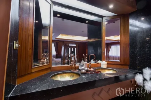 Condominium for rent or sale in Ratchathewi, Bangkok - Elegant bathroom featuring a granite double vanity with brass sinks and wood-framed mirrors.