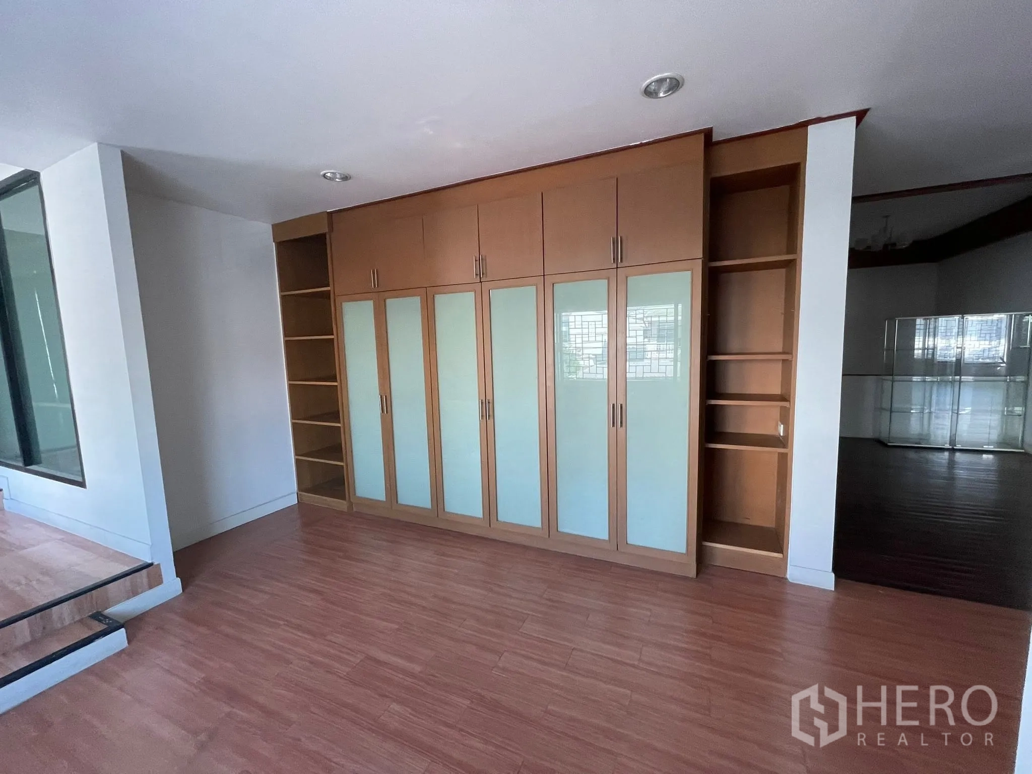 Detached House for rent or sale in Lam Luk Ka, Pathum Thani - Room with long wooden built-in wardrobe with frosted glass panels and wood flooring.