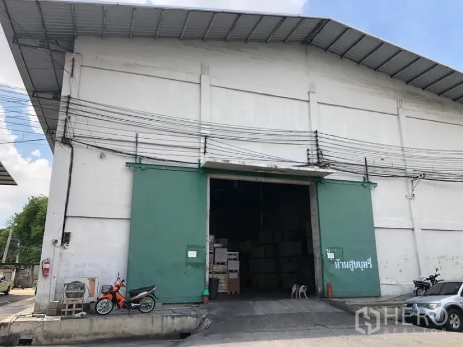Warehouse for rent in Rat Burana, Bangkok - High-roof industrial warehouse exterior with large green steel doors, a wide loading entrance and a paved forecourt in Rat Burana, Bangkok.
