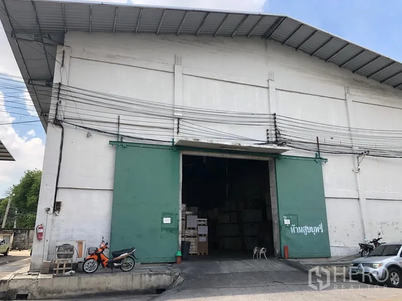 Warehouse for rent in Rat Burana, Bangkok - High-roof industrial warehouse exterior with large green steel doors, a wide loading entrance and a paved forecourt in Rat Burana, Bangkok.
