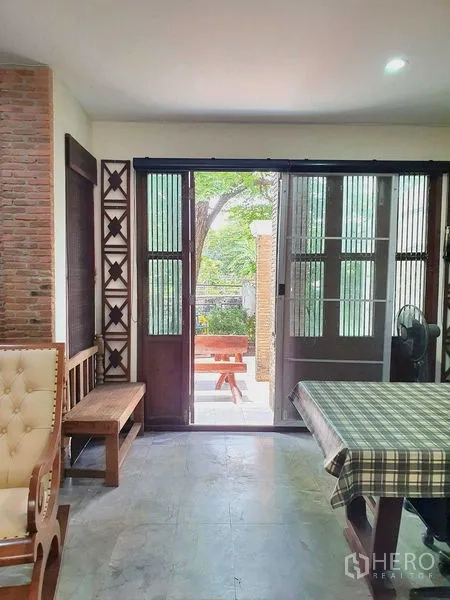 Townhouse for rent or sale in Suan Luang, Bangkok - Dining space with large wooden sliding doors leading to a patio with a picnic table.
