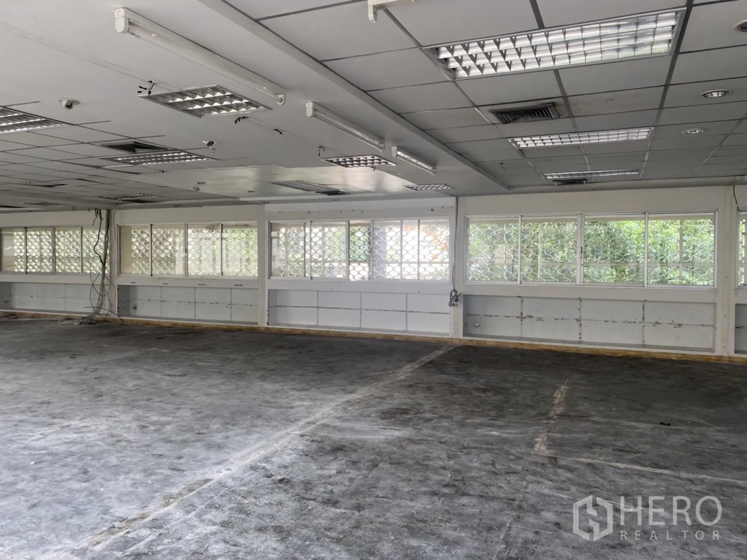 Office Space for rent in Khlong Toei, Bangkok - Open workspace with ribbon windows and exposed cabling along the wall, ready for fit‑out.