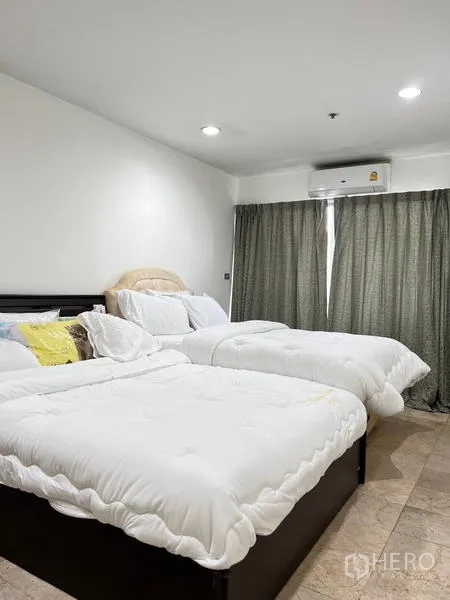 Condominium for rent in Ratchathewi, Bangkok - Second bedroom with two beds, blackout curtains and air conditioner.