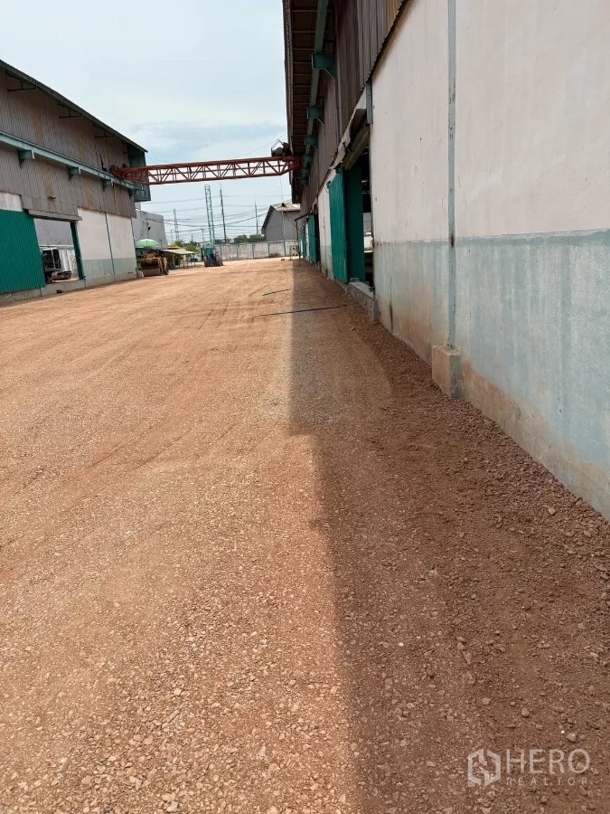 工厂 出租在Mueang Samut Sakhon, Samut Sakhon - 沿厂房侧面的长通道，夯实碎石地面与管线设施。